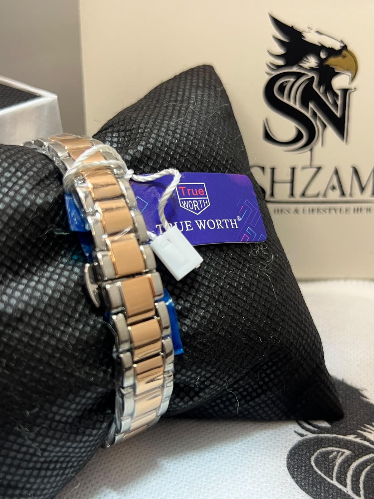 True Worth Ladies Watch two-tone silver and rose gold bracelet detail with True Worth brand tag on black pillow
