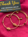 Gold Crystal Flower Cuff Bangle Pair showing both Ruby Red and White variants on pink fabric