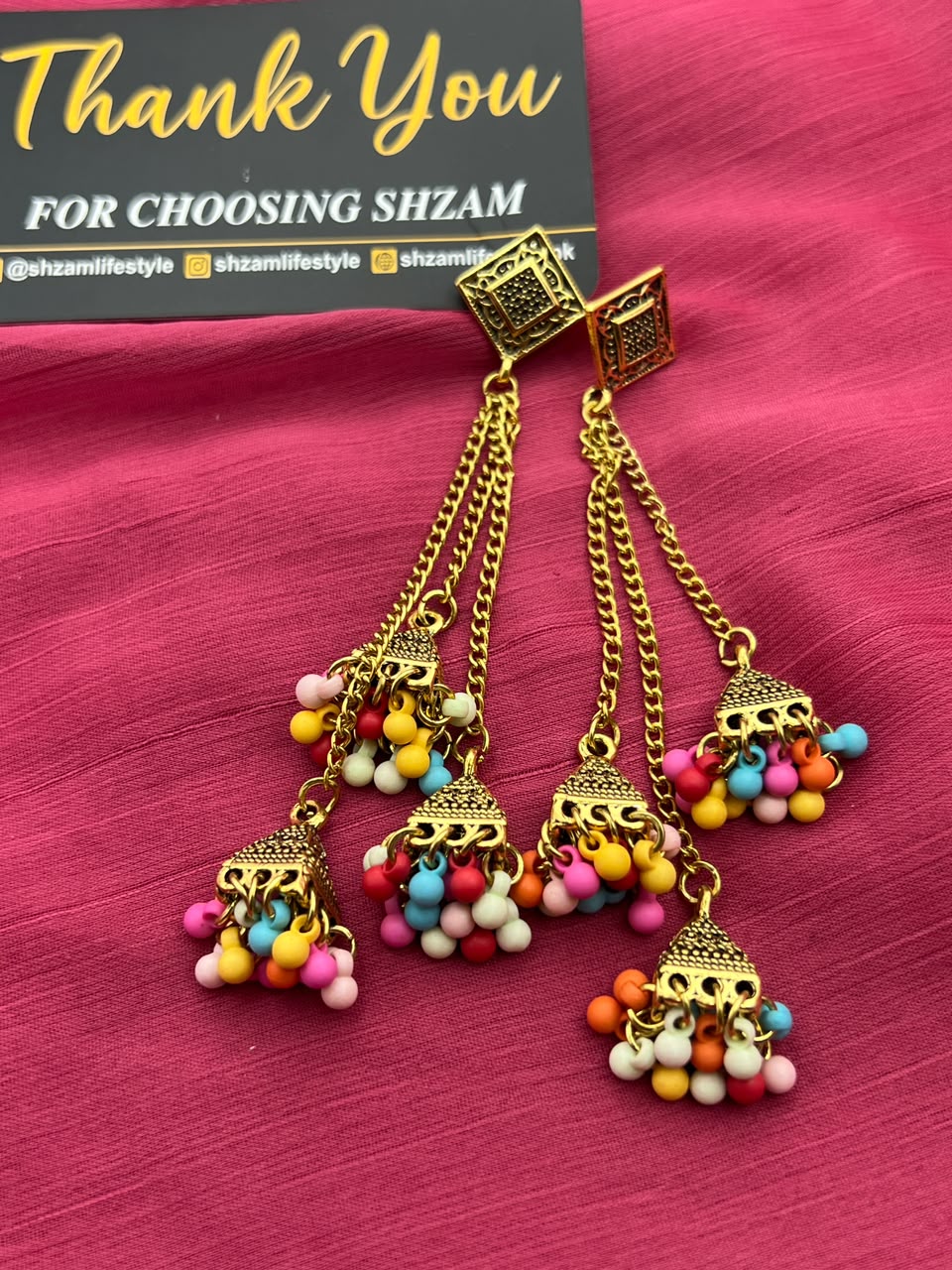 Multi-Color Antique Gold Tiered Jhumka Chandelier Earrings on pink fabric