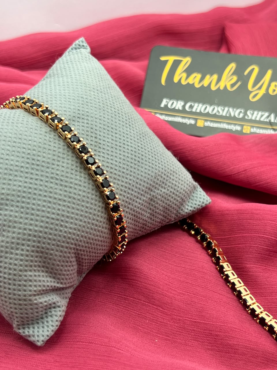 Two Black Diamond Tennis Bracelets on pillow and red fabric