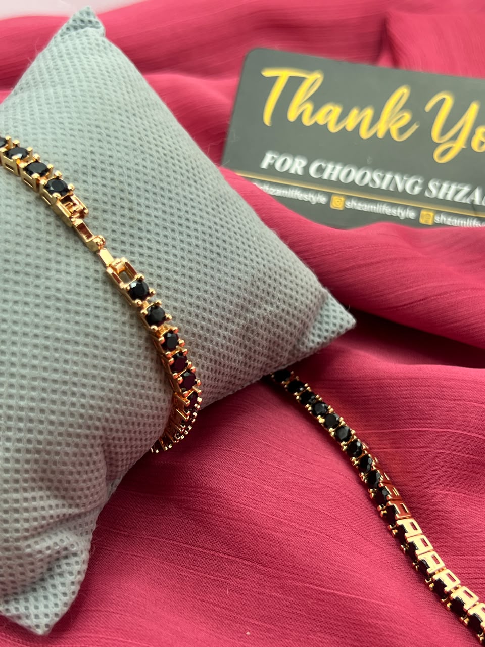 Two Black Diamond Tennis Bracelets on pillow and red fabric